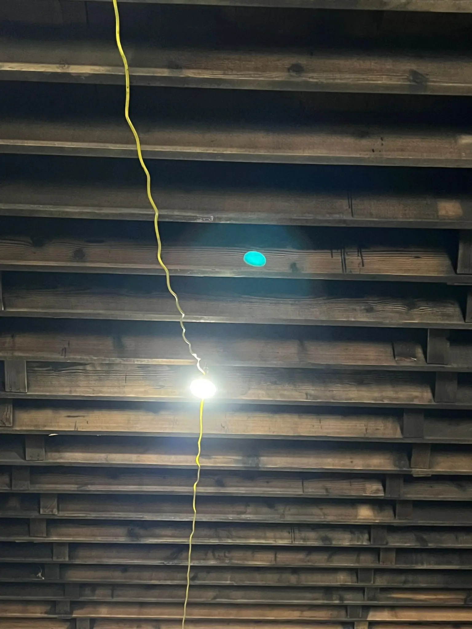 Fire-damaged roof structure — exposed rafters, moisture probe and work light deployed for assessment