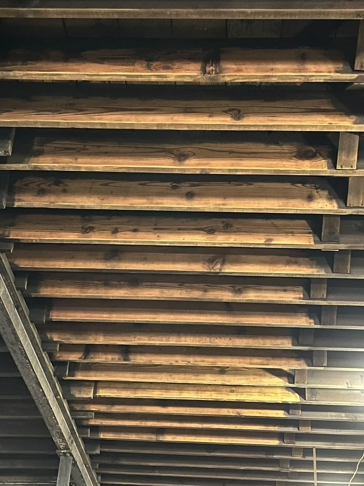 Detailed view of fire and smoke damaged roof decking — scorched boards documented for insurance scope