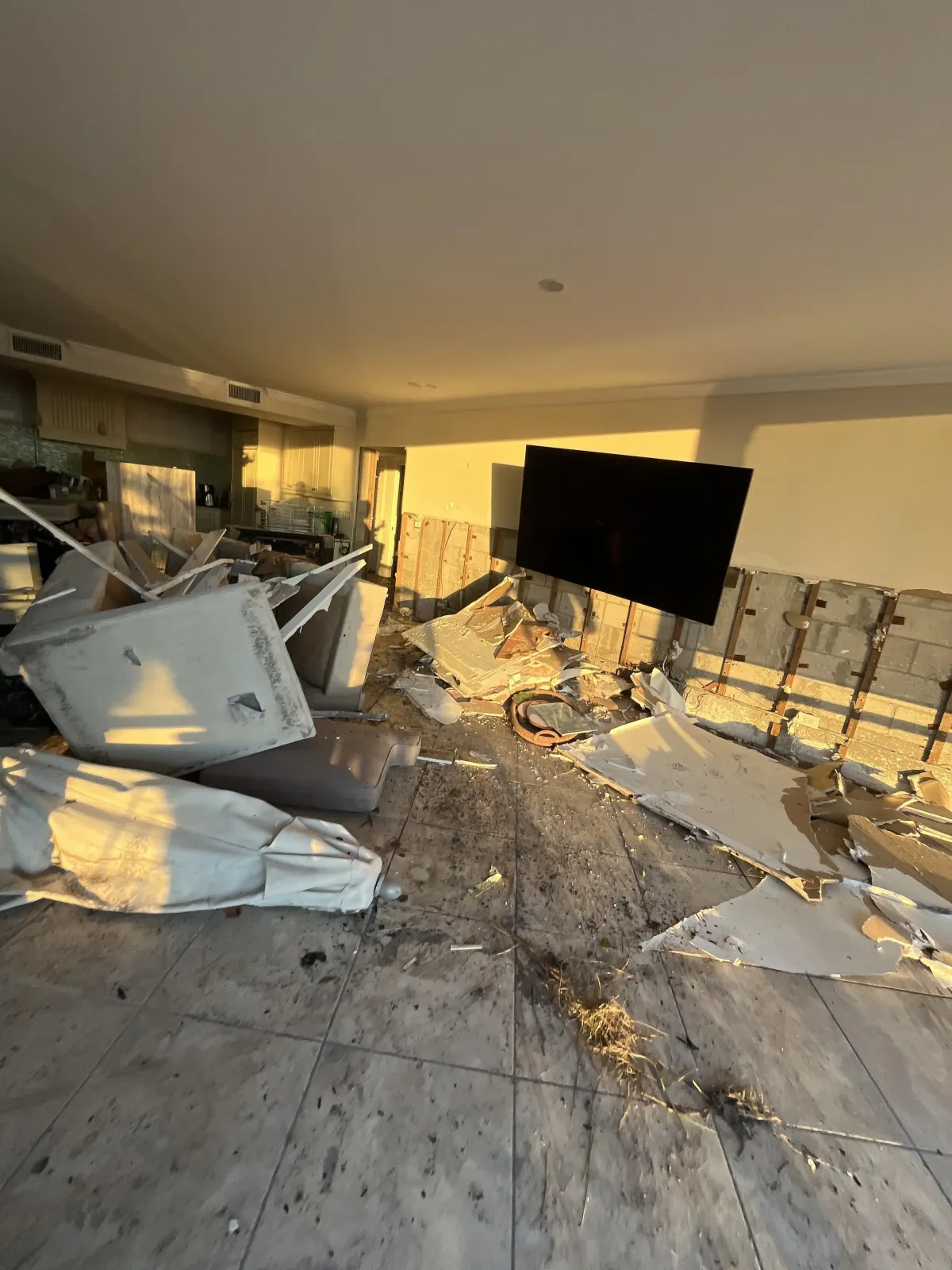 Storm loss interior — catastrophic structural damage, demolished drywall, debris field, walls stripped to CMU block