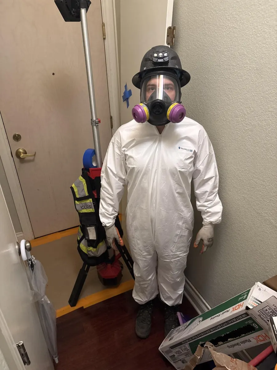 CCRS certified technician in full PPE — Tyvek suit, full-face respirator, hard hat — ready for mold remediation deployment
